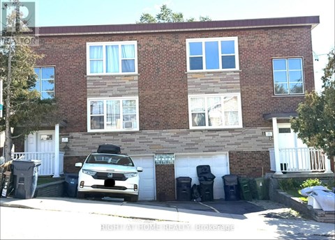 A white car is parked in front of a brick building.