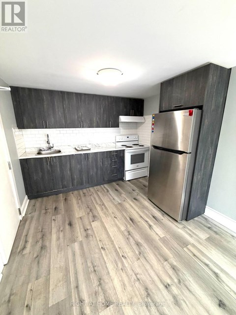 A kitchen with a refrigerator, stove, and sink.
