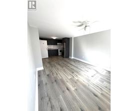 A room with a ceiling fan and wooden flooring.