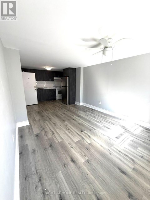 A room with a ceiling fan and wooden flooring.