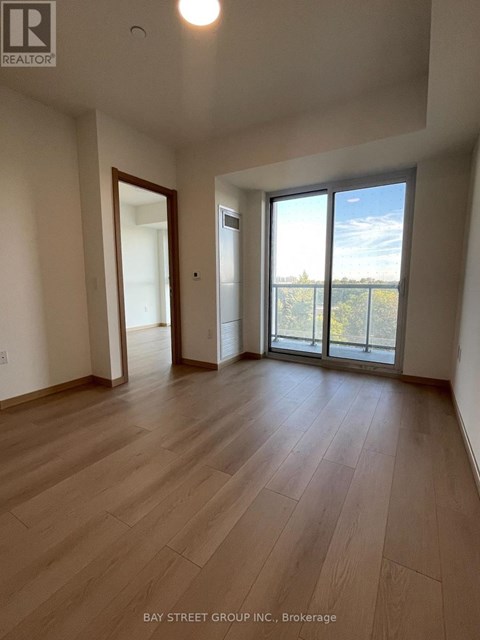 A spacious room with wooden flooring and sliding glass doors leading to a balcony.