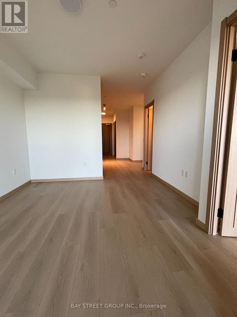 A room with wooden flooring and white walls, with a door on the right side.