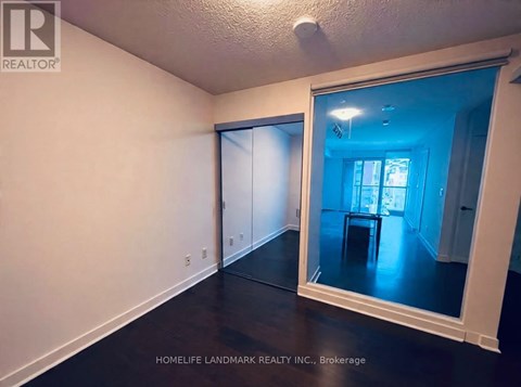 A room with a mirror showing a dining area.