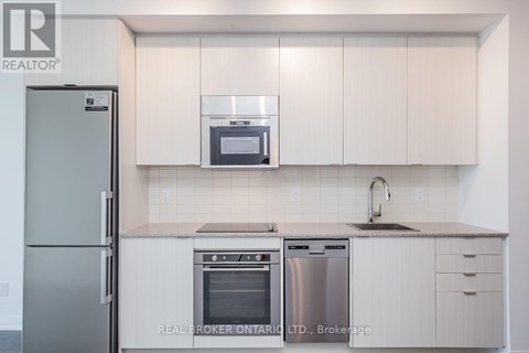 A modern kitchen with white cabinets and stainless steel appliances.