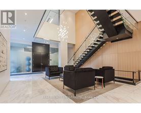 A modern living room with a staircase and a glass wall.