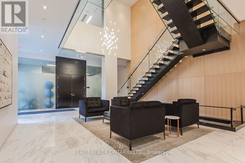 A modern living room with a staircase and a glass wall.