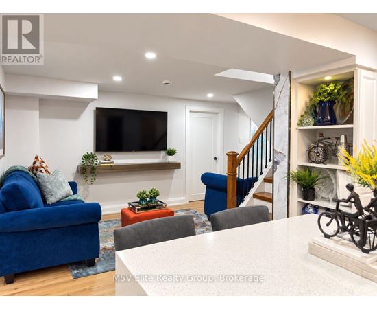 A living room with a blue couch and a television mounted on the wall.