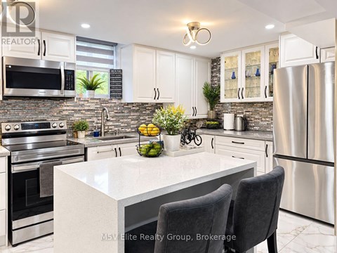 A modern kitchen with stainless steel appliances and a marble countertop.