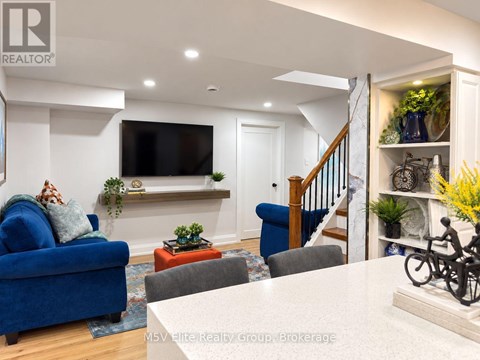 A living room with a blue couch and a television mounted on the wall.