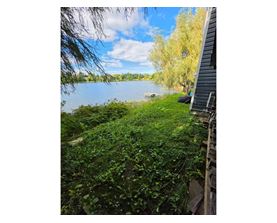 A lake surrounded by greenery and a building on the right side.