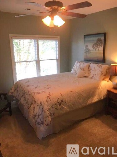 A bedroom with a large bed and a ceiling fan.