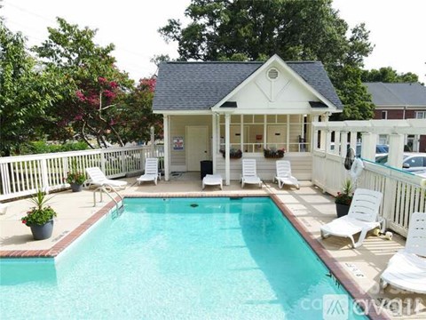 A pool with a white fence and a small house in the background.