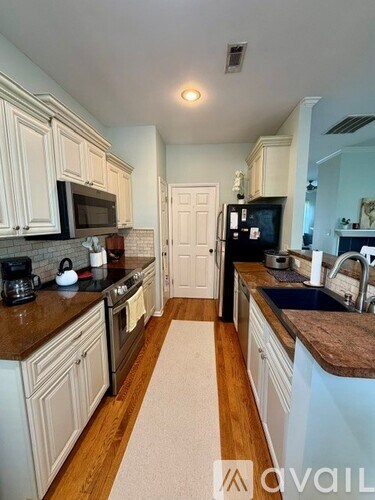 A kitchen with white cabinets and a brown countertop.
