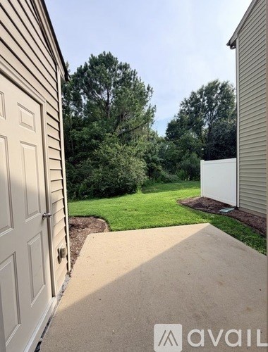 A white door is on the left side of a concrete walkway.