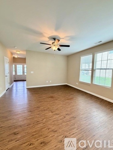 A spacious room with wooden flooring and a ceiling fan.