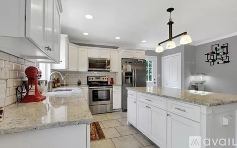 A modern kitchen with white cabinets and a marble countertop.