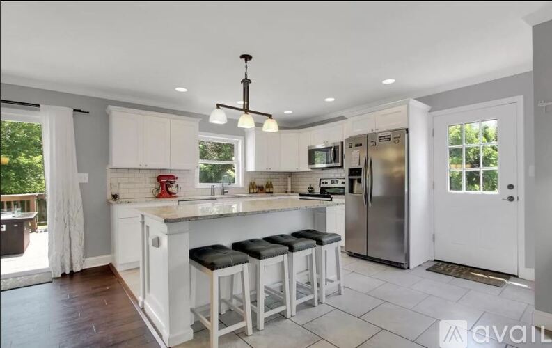 A kitchen with white cabinets and a central island with three stools.