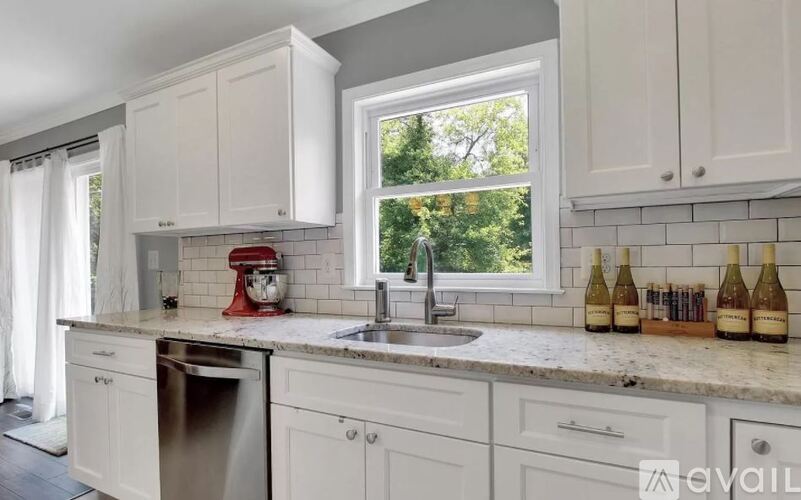 A kitchen with white cabinets and a red mixer.
