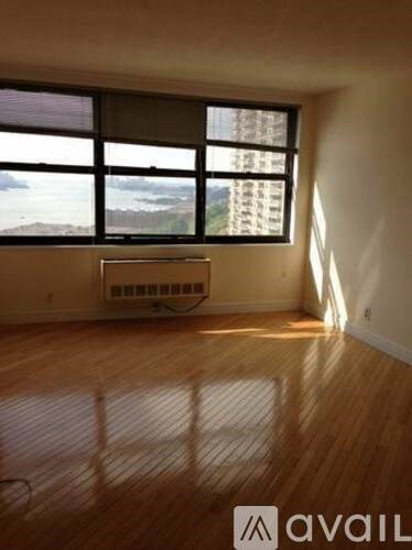 A room with wooden floors and a window overlooking a cityscape.