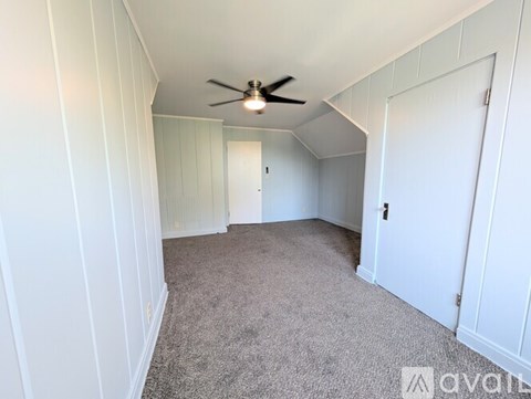 A room with a ceiling fan and carpeted floor.