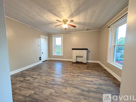 A spacious room with wood flooring and a fireplace.