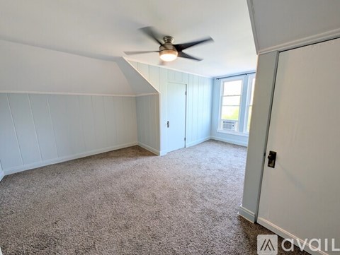 A room with a ceiling fan and carpeted floor.