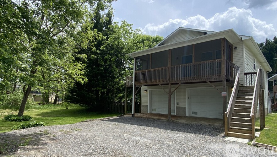 A house with a garage and a deck is surrounded by trees.