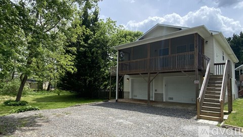 A house with a garage and a deck is surrounded by trees.