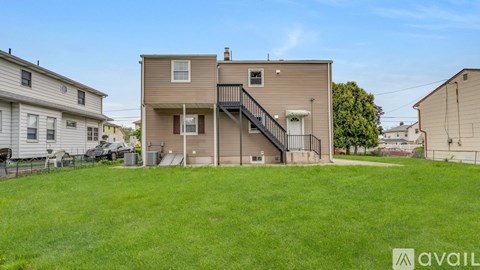A grassy area in front of a two-story house with a garage.
