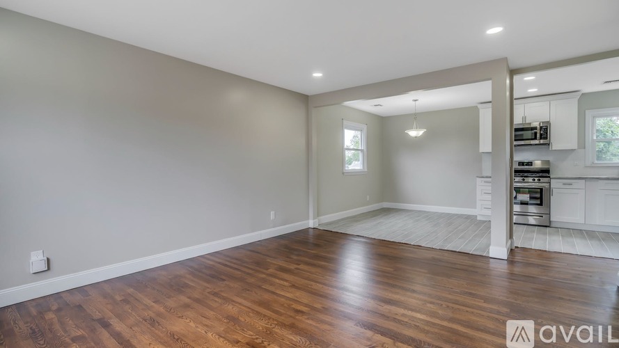 A spacious room with wooden flooring and white walls.