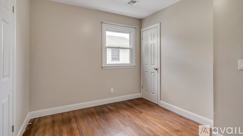 A room with wooden floors and a window with blinds.