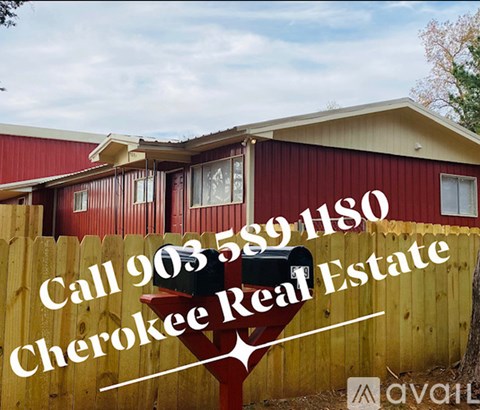 A red building with a sign that says "Call 903 559 1180 Cherokee Real Estate".