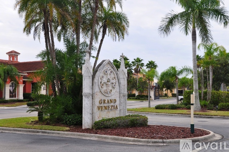 A sign for Grand Venezia is in the foreground of a street with palm trees.