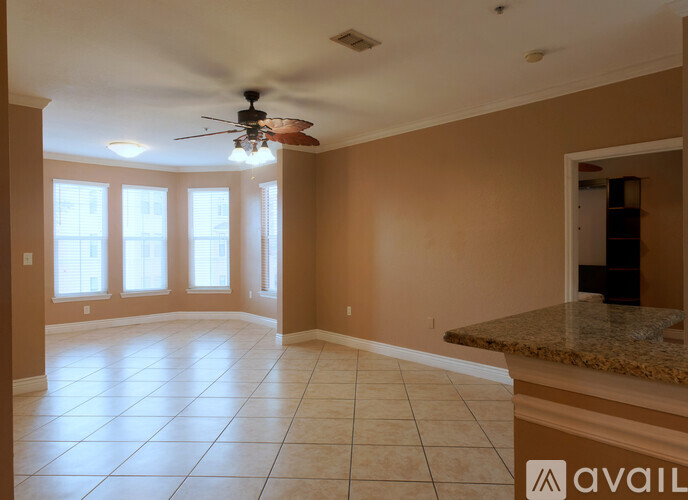 A spacious room with a ceiling fan and large windows.