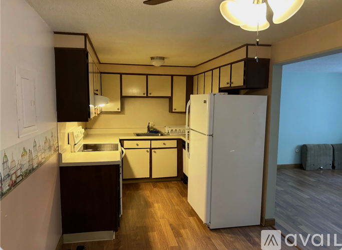A kitchen with a white refrigerator and wooden floors.