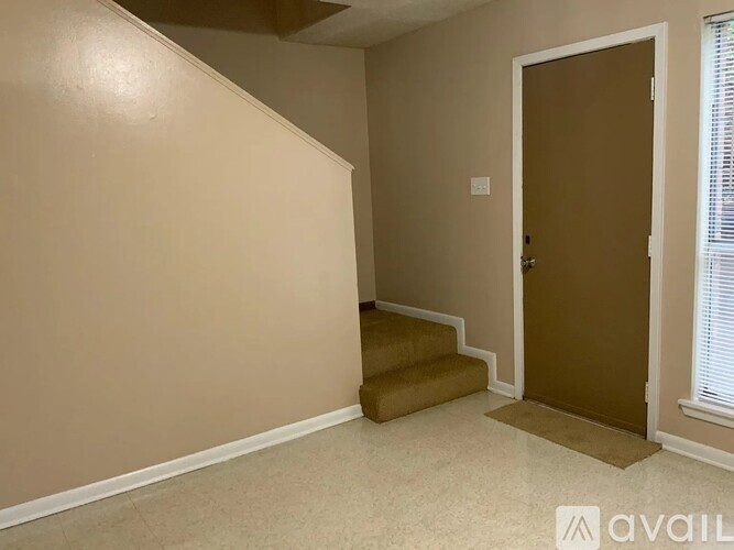 A room with a brown door and stairs leading to it.