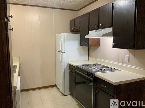 A kitchen with a white refrigerator, black cabinets, and a black stove top.