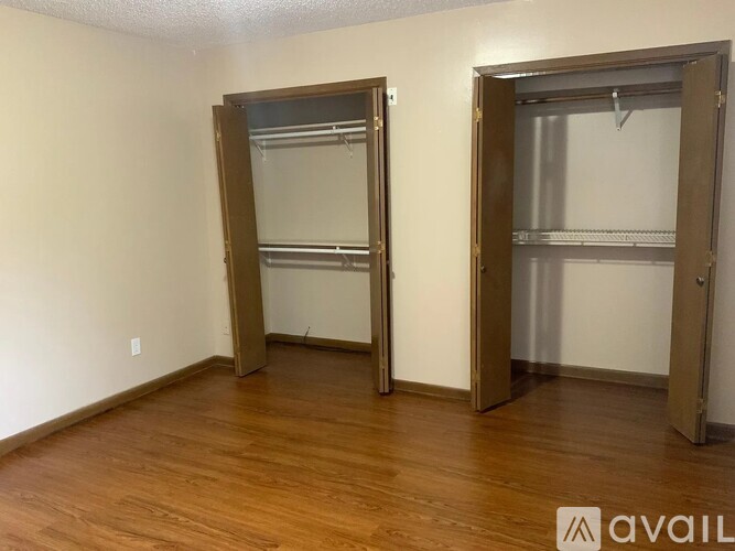 Two open closet doors with shelves and a wooden floor.