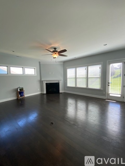 A spacious room with a fireplace and a ceiling fan.