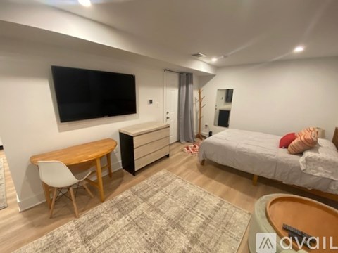 A bedroom with a bed, a desk, and a TV mounted on the wall.