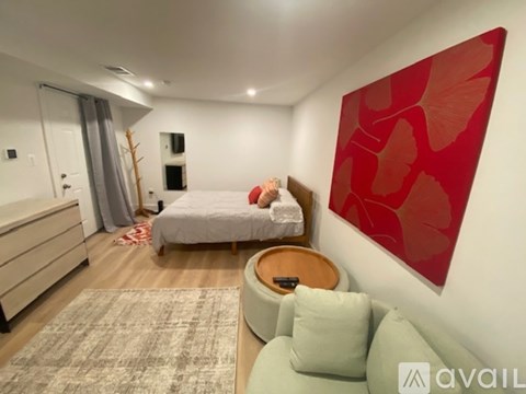 A bedroom with a bed, a chair, and a red leaf-patterned artwork on the wall.