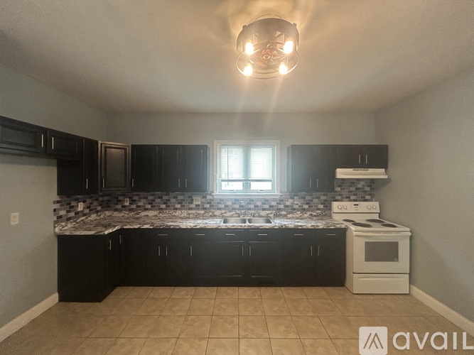 A kitchen with black cabinets and a white stove top oven.