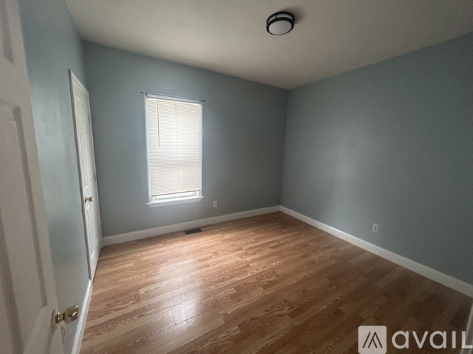 A room with wooden flooring and a window with blinds.