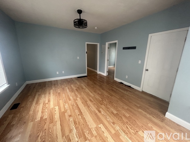 A room with wooden flooring and three doors.