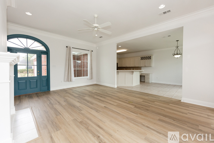 A spacious room with wooden flooring and a ceiling fan.