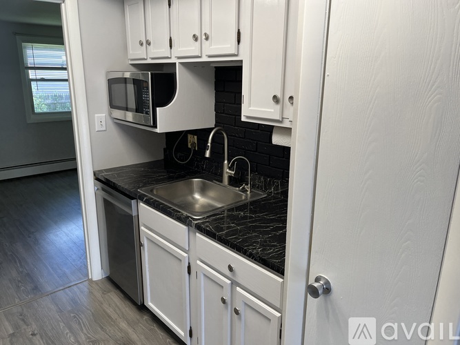 A kitchen with white cabinets and a black countertop.
