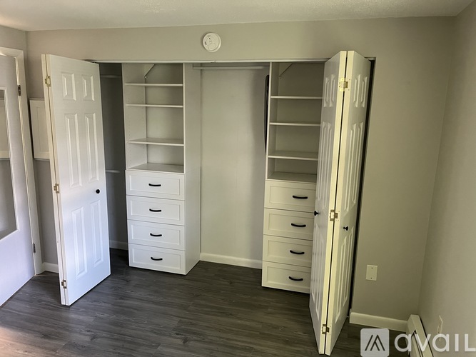 A room with a white door, a white dresser, and a white closet.
