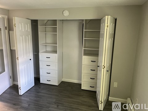 A room with a white door, a white dresser, and a white closet.