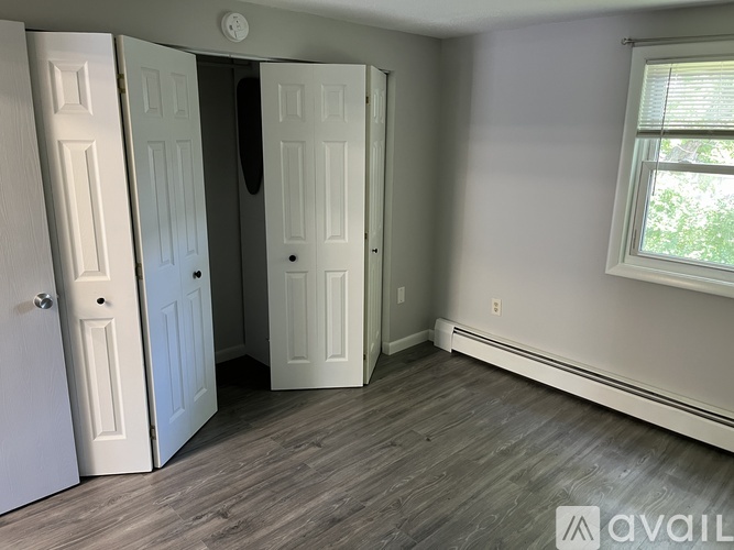 A room with a wooden floor and a window with a white frame.