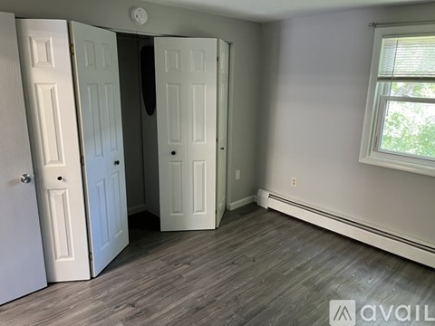 A room with a wooden floor and a window with a white frame.